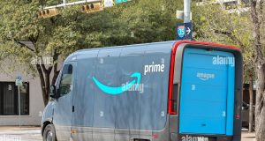 Amazon warehouse worker sorts boxes labeled essential items during coronavirus lockdown
