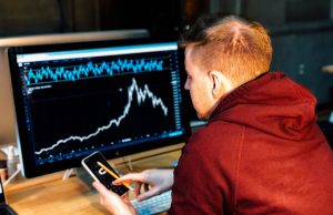 Asian Markets Diverge Ahead of US Jobs Report Traders monitor screens showing mixed Asian market indexes in a bustling stock exchange trading floor.