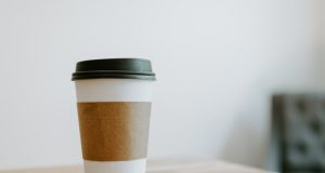 A reusable cup sits on a cafe counter in Singapore, with a sign reading Bring Your Own Cup.
