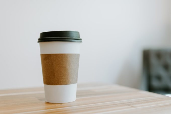 A reusable cup sits on a cafe counter in Singapore, with a sign reading Bring Your Own Cup.