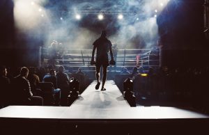 Lauren Price Unifies Welterweight with Five Titles Lauren Price in a boxing ring wearing championship belts after unifying the welterweight division.