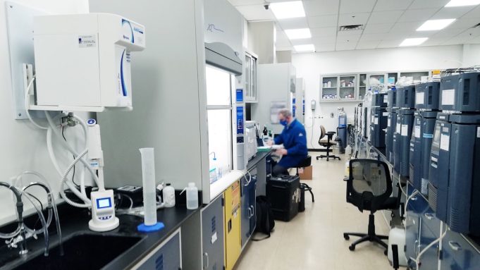 Kyntra Bio Rises from FibroGen's Ashes with Single Experimental Drug A scientist in a lab coat examines a vial labeled with an experimental cancer drug in a modern laboratory setting.