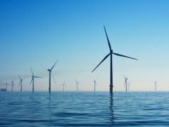 Solar panels and wind turbines stretch across a Chinese landscape under a clear blue sky.