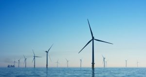 Solar panels and wind turbines stretch across a Chinese landscape under a clear blue sky.