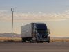 Tesla Semi truck parked at a charging station with Giga Nevada facility in the background