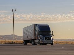 Tesla Semi truck parked at a charging station with Giga Nevada facility in the background