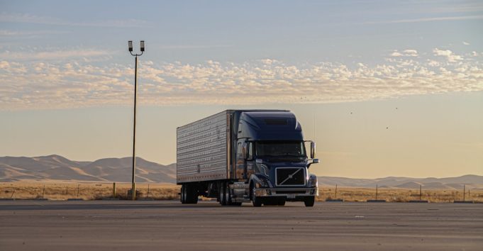Tesla Semi truck parked at a charging station with Giga Nevada facility in the background