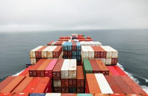 Russian Missile Hits China-Bound Iron Ore Ship A damaged cargo ship with a Liberian flag sits in a Ukrainian port after a missile strike, with smoke rising from the deck.