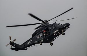 A Bell 212 helicopter in flight over mountainous terrain, with twin engines and two blades visible, representing the aircraft involved in the Iran crash.