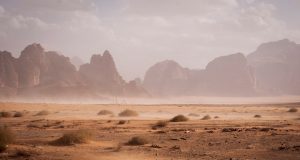 Kufra Crash Kills 12 Sudanese Migrants A damaged vehicle lies overturned on a desert road near the Kufra oasis, with emergency responders nearby.