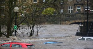Central Texas Flood Kills 51, 27 Children Missing Floodwaters engulf a residential street in Central Texas, with submerged cars and debris visible near homes.