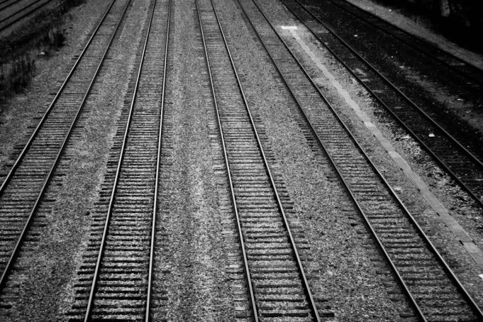 A sealed train boxcar sits on tracks in a Texas rail yard, surrounded by emergency vehicles and investigators.