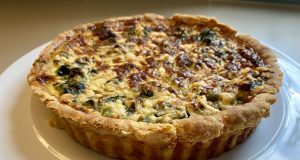 King Charles Coronation Quiche Debuts May 2023 A coronation quiche with spinach, broad beans, and tarragon on a serving platter at a royal celebration.