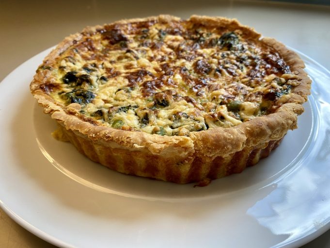 Coronation quiche A coronation quiche with spinach, broad beans, and tarragon on a serving platter at a royal celebration.