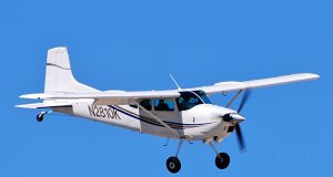 Cessna 180 Crash Kills Three in Nebraska River Rescue boats circle a partly submerged white Cessna 180 in the muddy Platte River as crews work along the wooded bank under gray skies.