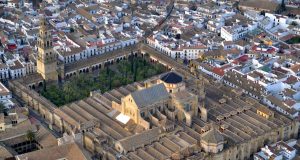 Córdoba Mosque-Cathedral Fire Collapses Chapel Roof Orange flames and smoke billow from the chapel roof of the striped-arch Mosque-Cathedral while firefighters spray water hoses at night.