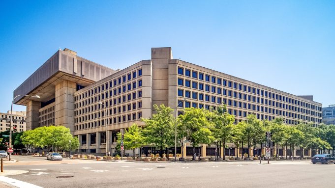 Fbi Headquarters J Edgar Hoover Building A grainy monochrome image with a central crosshair reticle shows a small dark circular object in the upper right quadrant against an indistinct mountain range.