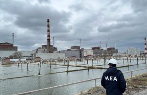 IAEA Deploys Teams to All Ukraine Nuclear Plants IAEA Director General Rafael Grossi stands with Ukrainian officials at a nuclear plant, raising the agency's flag beside Ukraine's flag.