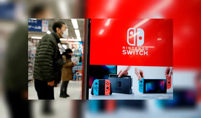 Nintendo Switch consoles and Joy-Con controllers on a factory assembly line in China, with workers in protective masks amid the coronavirus outbreak.