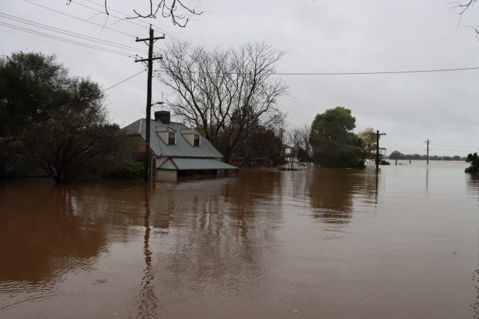 Flood death toll in Pakistan reaches 55, including eight children Floodwaters engulf a residential area in Pakistan during the monsoon season, with submerged homes and debris visible.