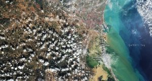 Spain Floods Kill Hundreds in Valencia, Andalusia Regions Murky brown floodwater surges through a Spanish town street, half-submerging cars and ground-floor shops under a still-grey sky.