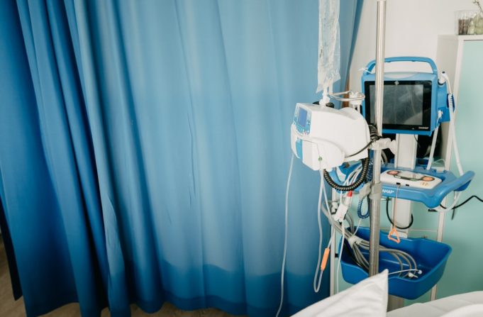 WHO Ends COVID-19 Emergency, but Long COVID Challenges Persist for Millions A healthcare worker checks on a patient in a hospital bed, representing ongoing long COVID care after the emergency phase ends.