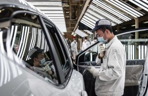 Workers stand outside a closed Renault factory gate in Wuhan as Chinese authorities enforce a strict quarantine lockdown.