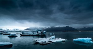 Antarctic Ice Sheet Melt Could Raise Seas 60 Meters A massive Antarctic ice sheet stretches across the horizon under a pale blue sky, with penguins gathered on a rocky outcrop in the foreground.