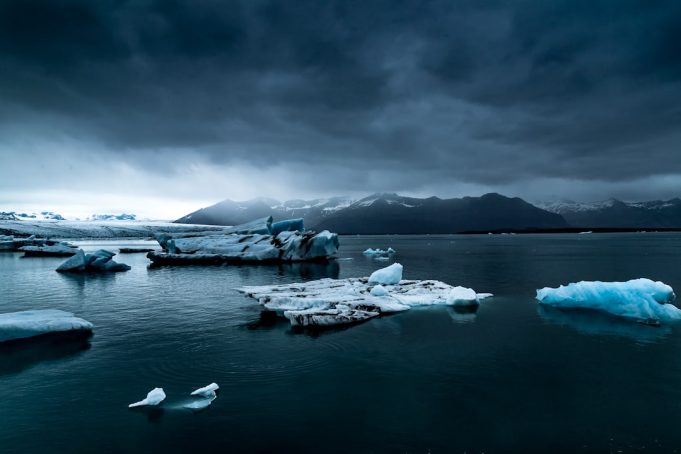 Antarctic Ice Sheet Melt Could Raise Global Sea Levels by 60 Meters A massive Antarctic ice sheet stretches across the horizon under a pale blue sky, with penguins gathered on a rocky outcrop in the foreground.