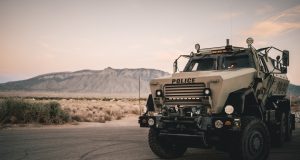 Kata’ib Hezbollah Suspends US Attacks in Iraq Armed militia members in uniform stand near military vehicles in Iraq, representing Kata'ib Hezbollah's state-sanctioned brigades.