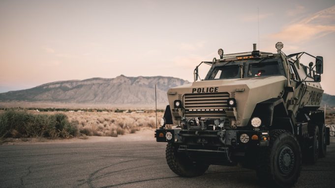 Kata'ib Hezbollah Suspends US Attacks to Avoid Embarrassing Iraqi Government Armed militia members in uniform stand near military vehicles in Iraq, representing Kata'ib Hezbollah's state-sanctioned brigades.