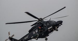 A Bell 212 helicopter in flight over mountainous terrain, with twin engines and two blades visible, representing the aircraft involved in the Iran crash.