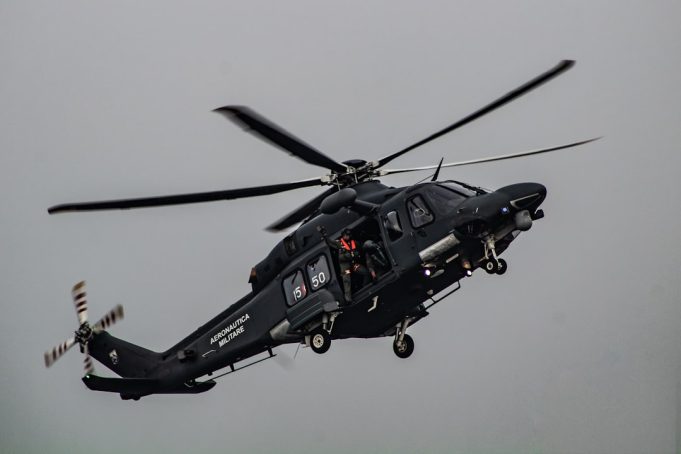 A Bell 212 helicopter in flight over mountainous terrain, with twin engines and two blades visible, representing the aircraft involved in the Iran crash.