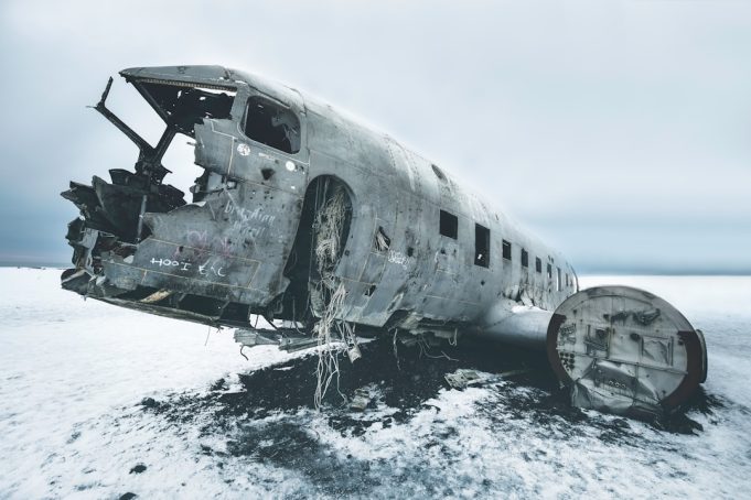 Fire crews spray foam on a burning twin-turboprop aircraft beside the Southend runway at dusk.